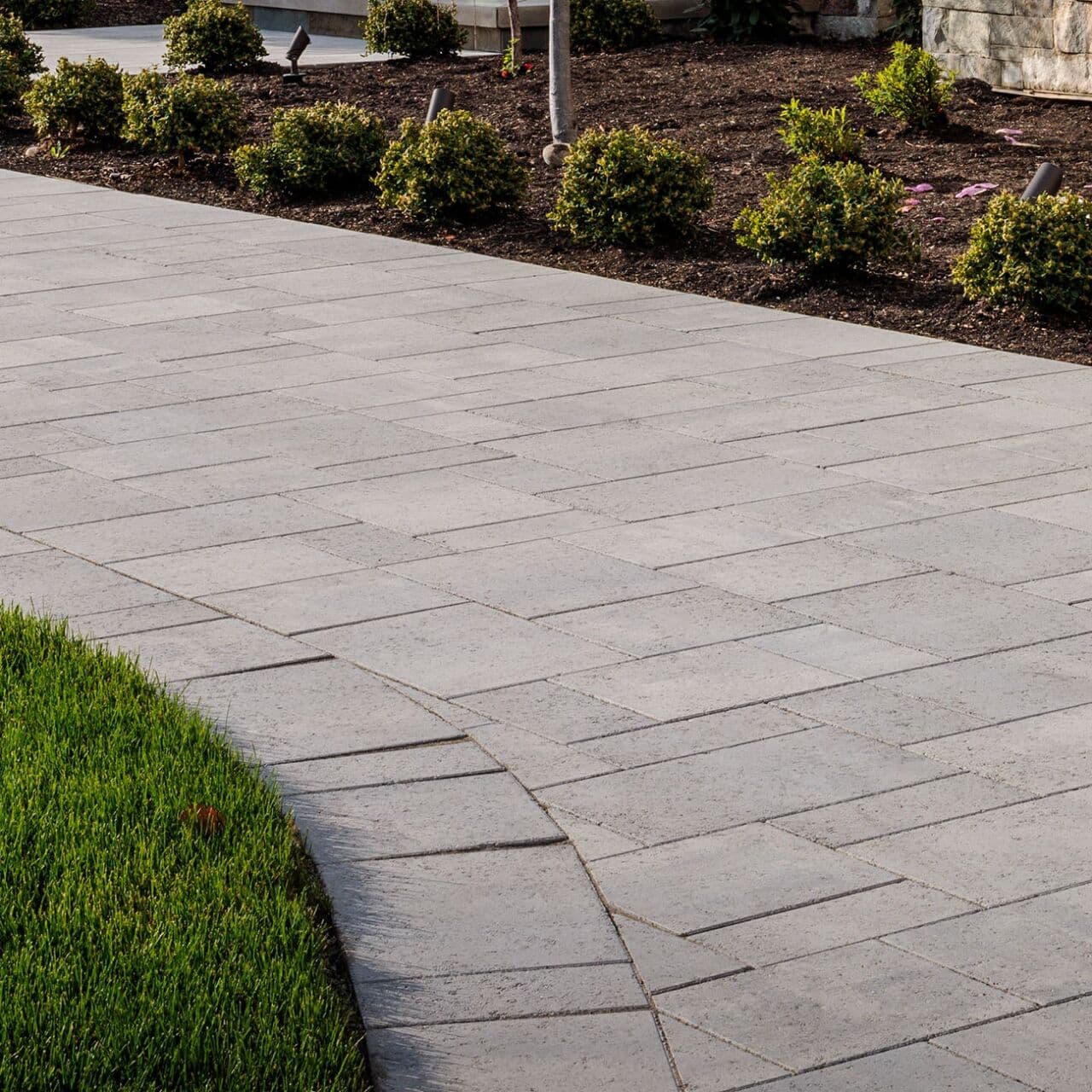 Large-format modular slab walkway with tight joints and a fan-cut curved transition beside a lawn — Daedalus Contracting, Lower Mainland BC